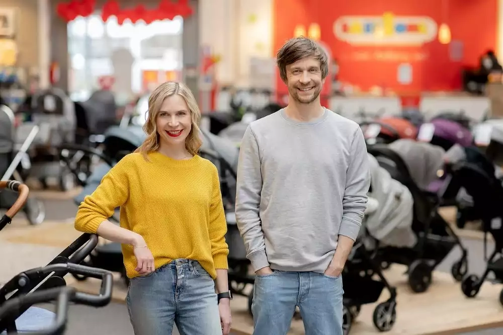 Ein mann und eine frau stehen gemeinsam neben einer baby-kutsche.