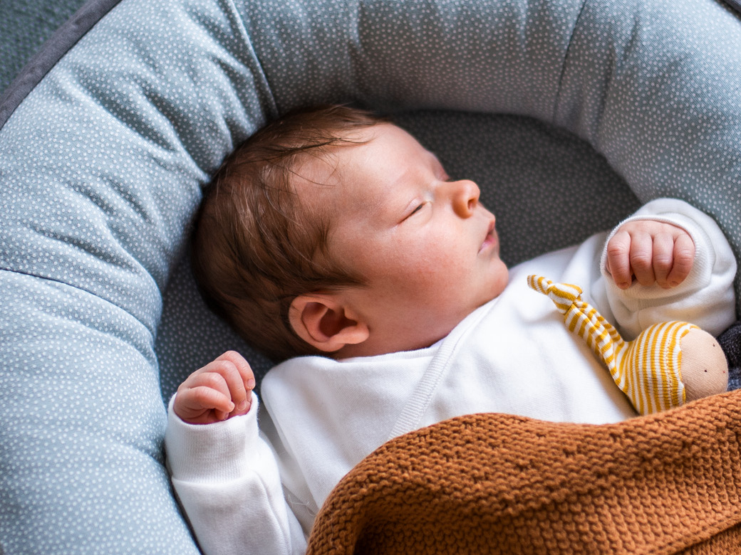 Baby schläft unter eine brauen Strickdecke.