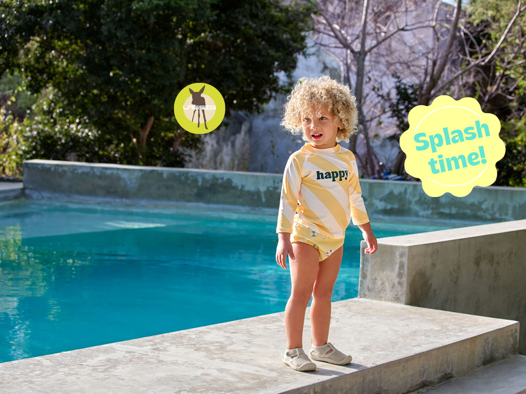 Kind mit UV Schutz Kleidung von Lässig steht am Pool. Splash time!