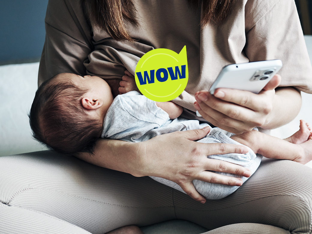 Frau stillt Baby und schaut dabei aufs Handy - Sprechblase wow