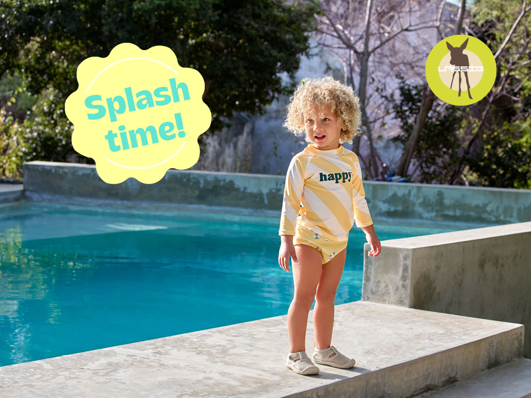 Kind mit UV Schutz Kleidung von Lässig steht am Pool. Splash time!