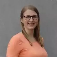 Eine frau in einem orangefarbenen hemd, die vor einer grauen.