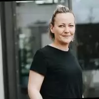 Eine frau in einem schwarzen hemd steht vor einem gebäude.