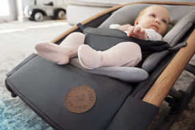 Baby ein, das in einem babysitz in einem wohnzimmer liegt.