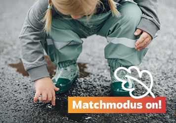 Mädchen mit Regensachen in einer Pfütze. Matschmodus on!