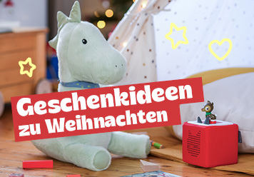 Geschenkideen zu Weihnachtn: Kuscheldrache, tonie Box, Bausteine und Buch abgebildet. Im Hintergrund eine Lichterkette und Tannengrün.