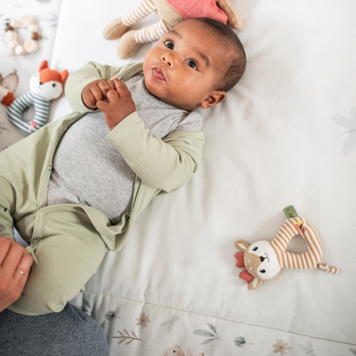 Baby ein, das auf einem bett mit ausgestopften tieren liegt.
