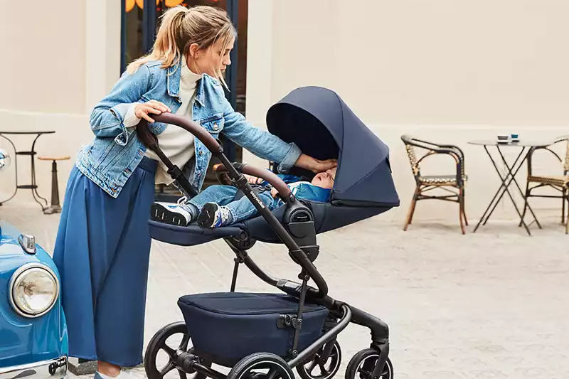 Eine frau, die ein baby in einen kinderwagen schiebt.