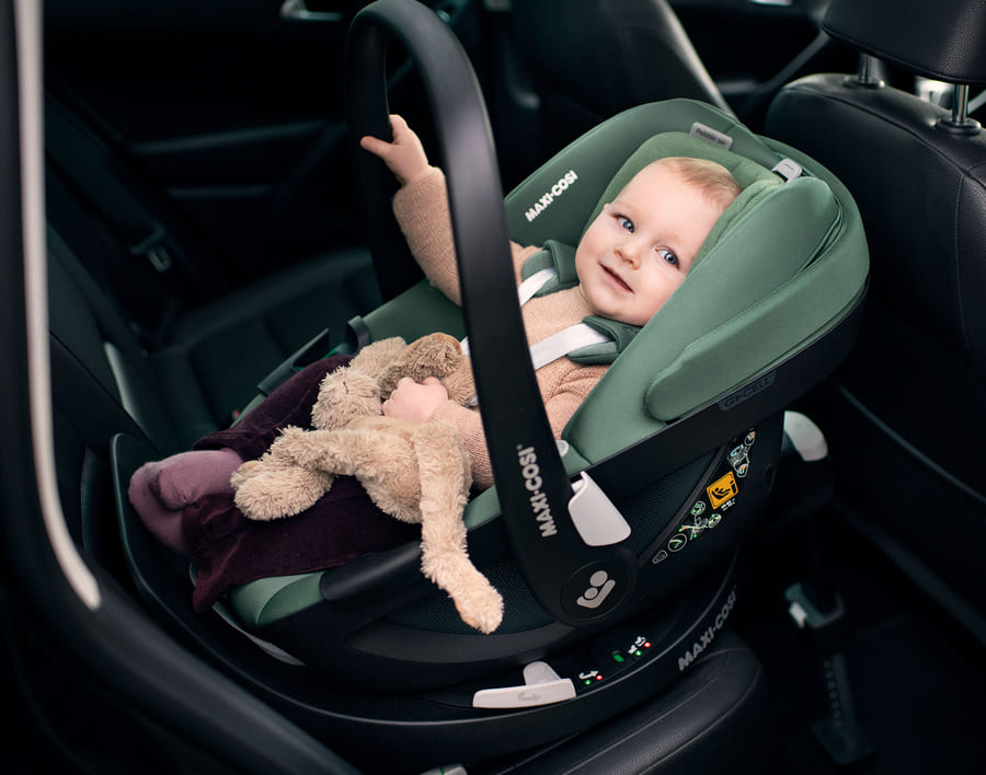 Baby ein auf einem autositz mit teddybär.
