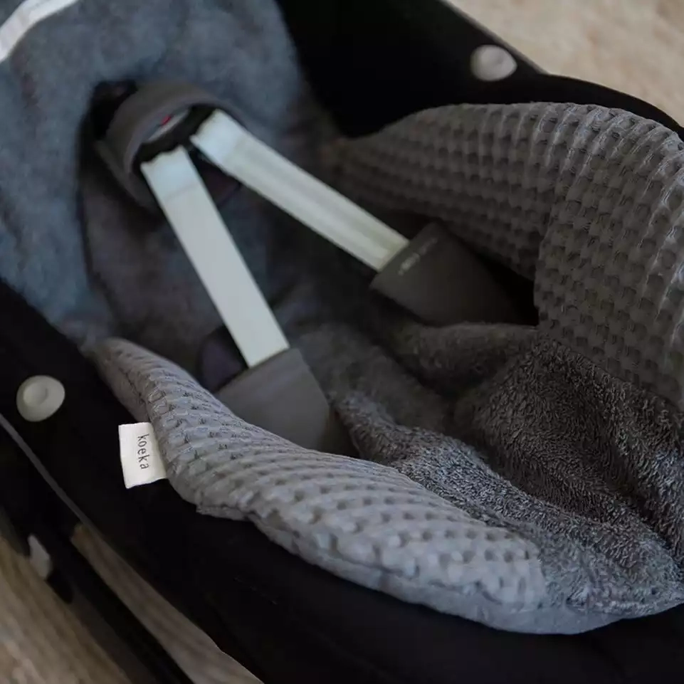 Baby ein autositz mit einer decke darauf.