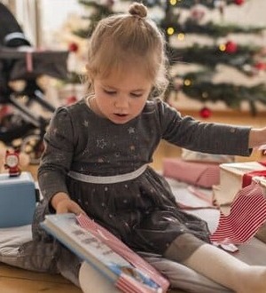 Mädchen sitzt auf dem Boden und packt Geschenke aus